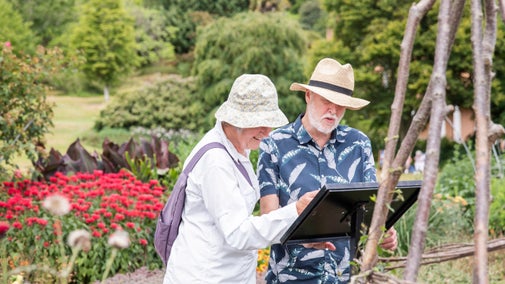Two visitors reading an information board in the garden at Killerton, Devon
